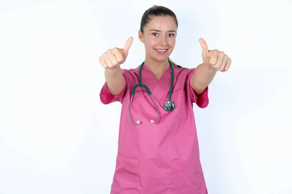 Biała Kobieta Lekarz Różowym Mundurze Stetoskopem Robi Pozytywny Gest Kciukami — Zdjęcie stockowe