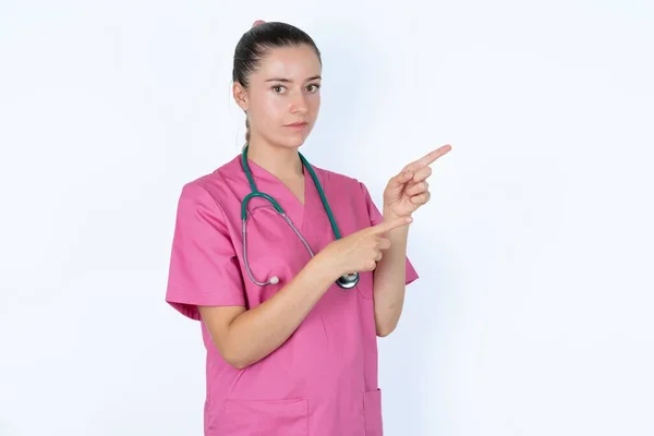 Médico Feminino Caucasiano Aponta Lado Com Expressão Surpresa Com Boca — Fotografia de Stock