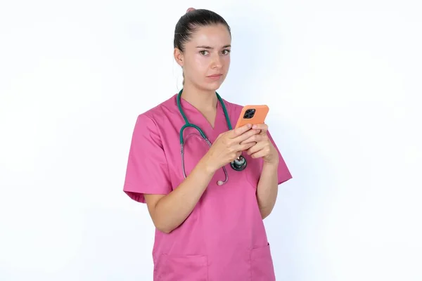 Porträtt Förvirrad Kaukasisk Kvinnlig Läkare Med Mobiltelefon Och Ryckande Axlar — Stockfoto