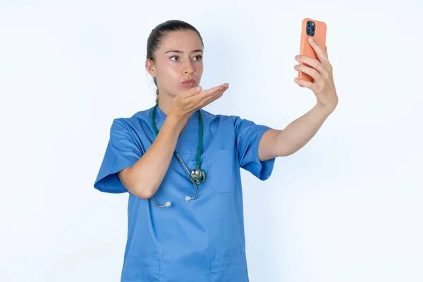 Kaukasisk Kvinnlig Läkare Blåser Luft Kyss Kameran Smartphone Och Tar — Stockfoto