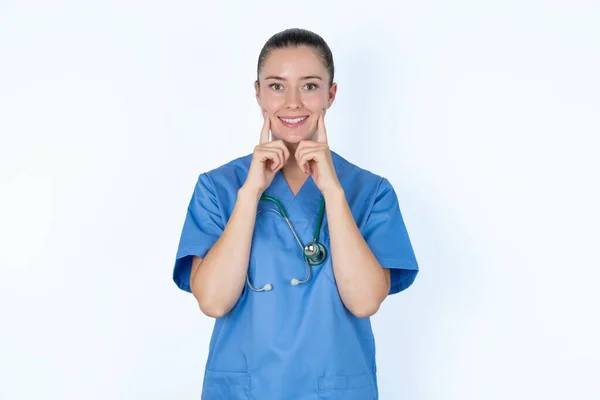 歯痛の笑顔の幸せな女性医師は 口の近くで指を指し 陽気な笑顔を強制する指を保ちます — ストック写真