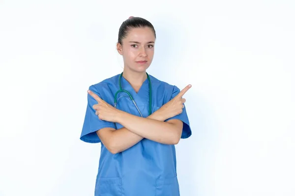 Serious Doctor Woman Crosses Hands Points Different Sides Hesitates Two — Stock Photo, Image