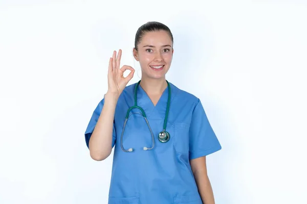 ステートスコープと制服の白人女性医師は 手の腕を保持する大丈夫なシンボルは 新鮮なニュースをアドバイスすることを承認 — ストック写真
