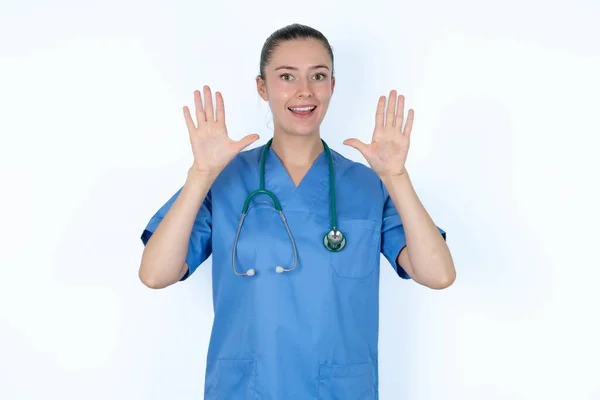 ステスコープの制服を着た白人女性医師は 大きな結果を得た後 口と腕の手のひらを開きます — ストック写真