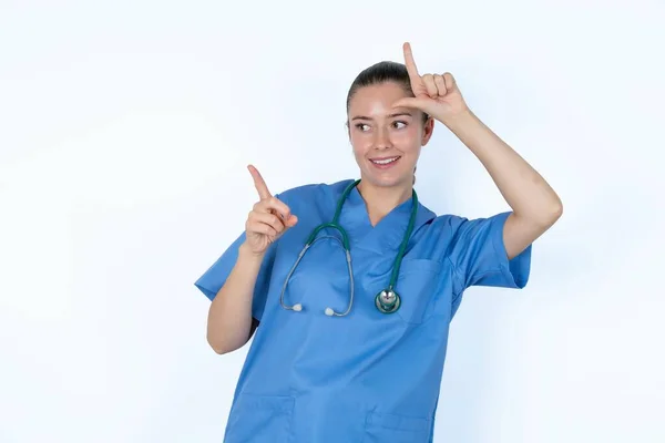 白人女性の医師は 失われたサインを示し 空のスペースを指す制服を着ています — ストック写真