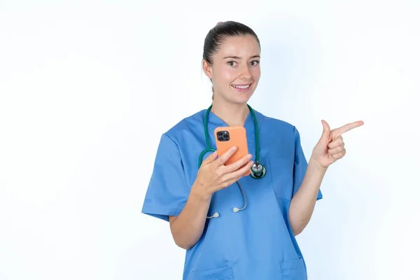 Doctora Caucásica Uniforme Con Estetoscopio Sosteniendo Teléfono Señalando Con Dedo —  Fotos de Stock