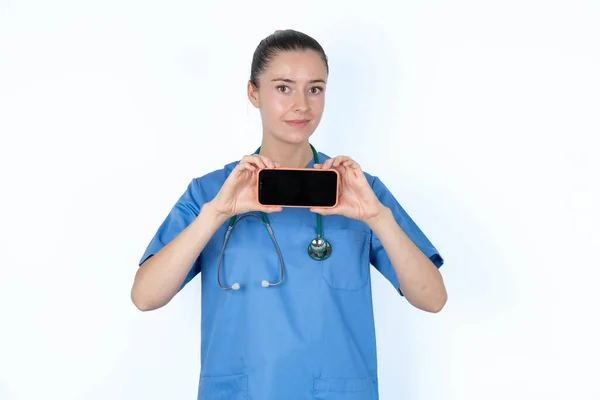 手の携帯電話で保持するステスコープと制服の白人女性の医師 — ストック写真