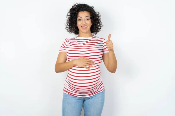 孕妇快乐的笑着双手放在肚子上显示出大拇指向上的健康 — 图库照片