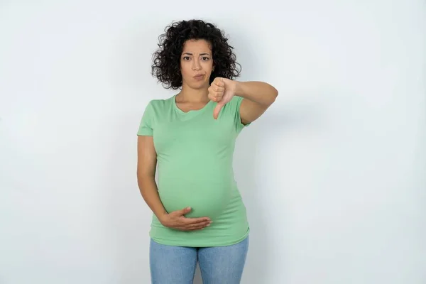 妊娠中の女性は親指を押し下げて拒絶反応と否定を示す不満と怒りを見ています 悪い表現 — ストック写真
