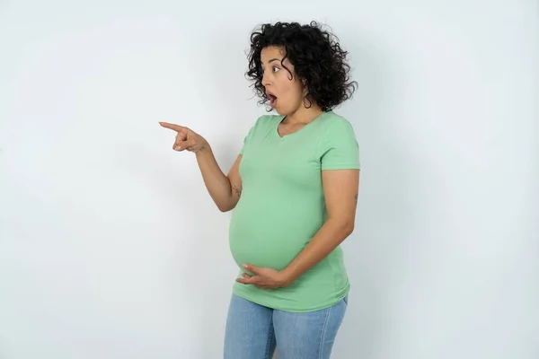妊娠中の女性を強烈に驚きの表情ポイント離れてコピースペースに 何かを示しています — ストック写真