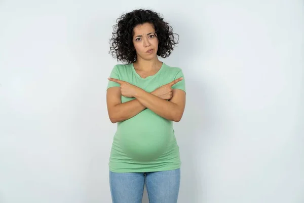 深刻な妊娠中の女性は 異なる側面で手とポイントを交差し 2つのアイテムの間に躊躇します ハード決定コンセプト — ストック写真