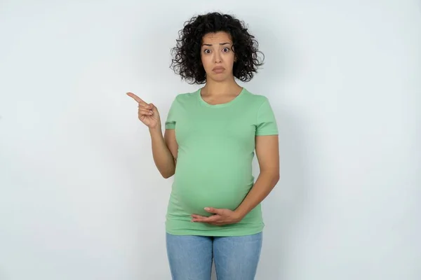 Serious Pregnant Woman Smirks Face Points Away Copy Space Shows — Stock Photo, Image