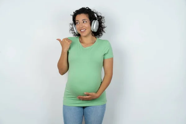 Těhotná Žena Poslouchá Audio Stopu Přes Bezdrátová Sluchátka Ukazuje Palec — Stock fotografie