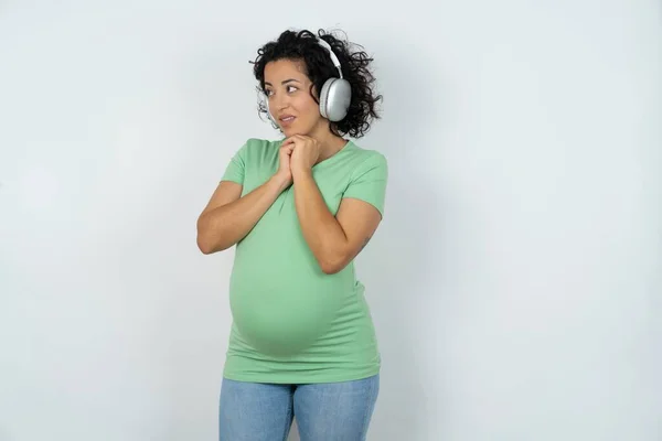孕妇戴着立体声耳机 聚精会神地听音乐 饶有兴趣地把目光投向一边 — 图库照片