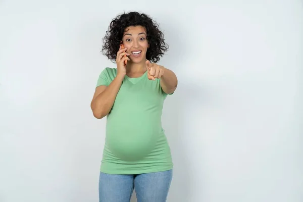 Pozitivní Těhotná Žena Ukazuje Přímo Kameru Bílý Telefonní Rozhovor Široce — Stock fotografie