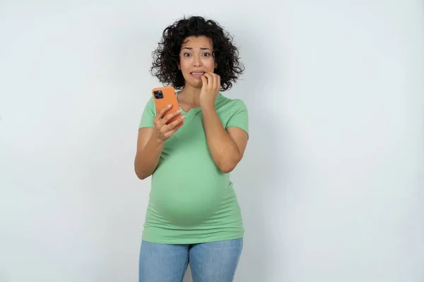 害怕有趣的孕妇拿着电话咬指甲 — 图库照片