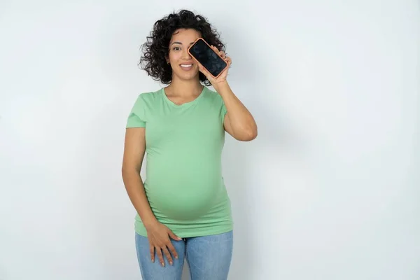 Těhotná Žena Drží Moderní Smartphone Zakrývá Jedno Oko Při Úsměvu — Stock fotografie
