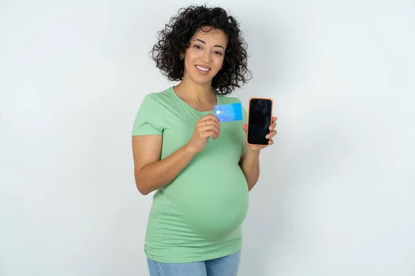 照片中可爱的孕妇拿着信用卡和智能手机 预留作网上购买 — 图库照片