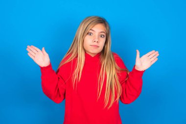 Belki evet ya da hayır. Şüpheli güzel beyaz kız mavi duvarın üzerine kırmızı kazak giyiyor şaşkınlık içinde omuz silkiyor, ne istediğine karar vermeye çalışıyor. Tereddüt ve belirsizlik.