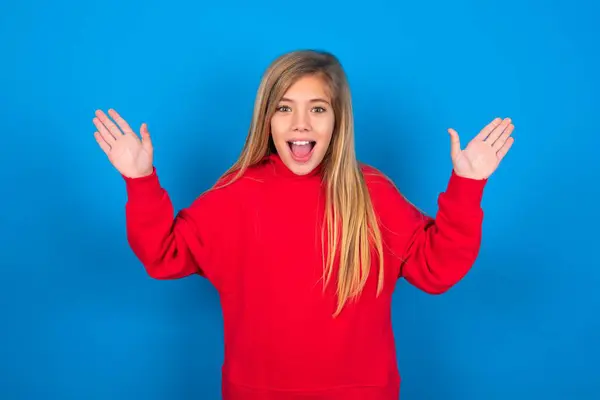 青い壁の上に赤いセーターを身に着けている美しい白人の十代の少女は 幸せに満ちた目で彼の偉大な業績を喜んでいます 成功コンセプト — ストック写真