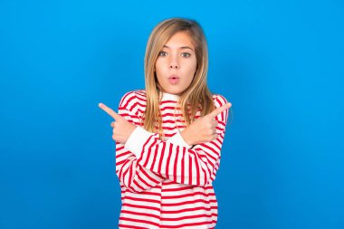 Kafası karışmış, mavi stüdyo geçmişi üzerinde çizgili tişört giyen beyaz bir kız iki taraftan birini seçiyor, her iki tarafı da çapraz ellerle işaret ediyor, şüphe duyuyor. Tavsiyene ihtiyacım var..