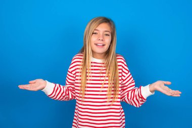 Ne olmuş yani? Mavi stüdyo arka planında çizgili tişört giyen güzel beyaz kız portresi omuz silkiyor, yan yana gülümsüyor, nefes nefese kalmış, bariz bir şey söylüyor..