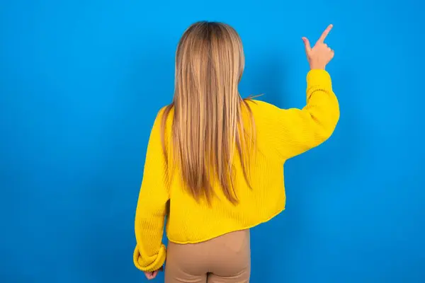Beautiful Blonde Teen Girl Wearing Yellow Sweater Blue Wall Pointing — Stock Photo, Image