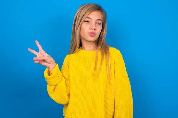 Hermosa Rubia Adolescente Chica Usando Suéter Amarillo Sobre Pared Azul —  Fotos de Stock