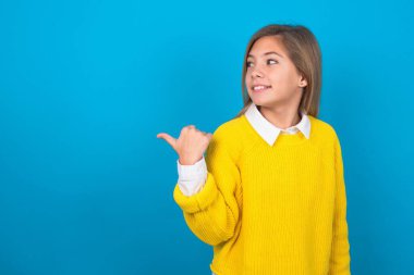 Mavi duvarın üzerinden sarı kazak giyen beyaz bir kız fotokopi odasına bakıyor ve reklam yapıyor.