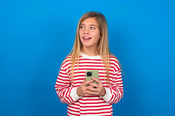 Rubia Adolescente Chica Usando Rayas Camiseta Sobre Azul Pared Sosteniendo —  Fotos de Stock