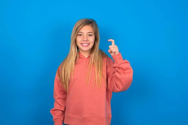 美丽的高加索少女 身穿粉色毛衣 翻过蓝色的墙壁 用手指头指指中国手语九号 — 图库照片