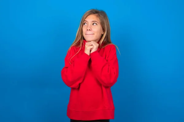 Ciekawa Blondynka Nastolatka Dziewczyna Czerwonym Swetrze Nad Niebieską Ścianą Trzyma — Zdjęcie stockowe