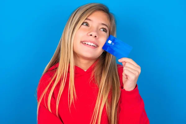 Gadis Pirang Cantik Mengenakan Sweater Merah Atas Dinding Biru Menunjukkan — Stok Foto