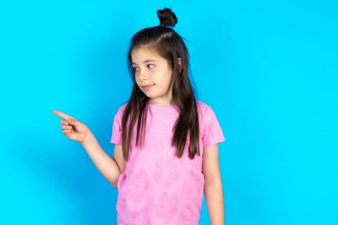 Çocuk fotokopi alanını işaret ediyor ve en uygun fiyat olan bir şeyin reklamını yapıyor. Güzel beyaz kız mavi stüdyo arka planında poz veriyor.