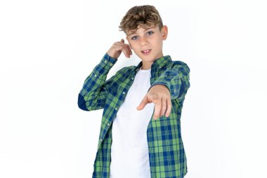 Beyaz stüdyo arka planındaki yakışıklı beyaz çocuk neşeyle gülümsüyor ve kameraya işaret ediyor. Daha sonra sana bir jest yapıyor, telefonla konuşuyor.