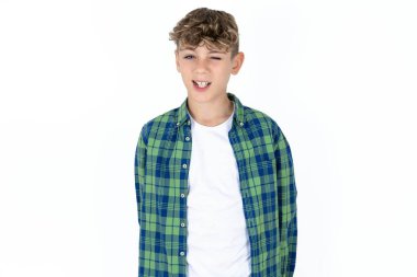 Beyaz stüdyo arka planında yakışıklı beyaz çocuk kameraya seksi bir ifadeyle bakıyor, neşeli ve mutlu bir yüzle..