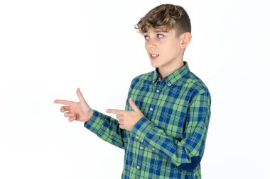 İyimser yakışıklı beyaz çocuk beyaz stüdyo arka planında iki eliyle ve boş alana bakıyor..