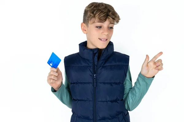 stock image Curious smiling handsome caucasian teenager boy on white studio background showing plastic bank showing finger copyspace