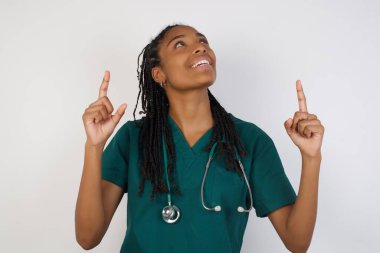 Başarılı, dost canlısı görünümlü, parlak makyajlı genç bir doktorun işaret parmağıyla işaret ederek boş bir fotokopi duvarında şok edici bir şey gösterdiği yatay görüntüsü..