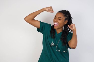 Evet, ben kazandım. Çekici, keyifli ve heyecanlı Afro-Amerikan doktor kadının portresi zafer ve zaferle yumruğunu kaldırıyor mutluluktan sırıtarak başarı elde ediyor..