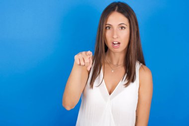 Şok olmuş genç bir kadın işaret parmağıyla kamerayı işaret ediyor ve... Sürpriz ve reklam konsepti.