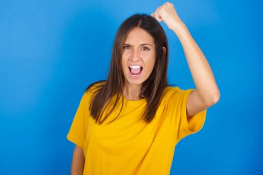 Şiddetli, genç ve güzel bir kadın, sanki dövüşmeye ya da meydan okumaya hazırmış gibi, bağırıyor ve yüzünde agresif bir ifade var..