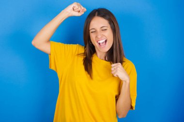 Çekici, güzel, genç bir kadın zaferi kutluyor yumruklarıyla havaya yumruk atıyor ve dişlek bir gülümsemeyle..