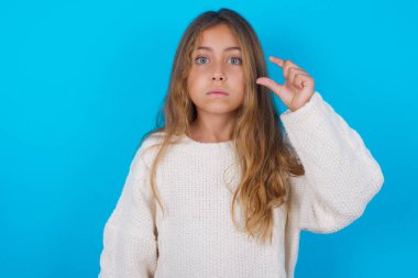 Güzel genç kız dudaklarını kesiyor ve el hareketleriyle çok küçük bir şey gösteriyor..