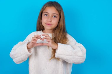 Ciddi, güzel bir genç kız ellerini çapraz tutuyor düşünceli bir şekilde duruyor.