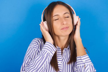 Kafasında kulaklıklarla güzel bir genç kadın müzik dinliyor. Gözü kapalı en sevdiği şarkıyı dinliyor. Kulaklıkla el ele tutuşuyor..