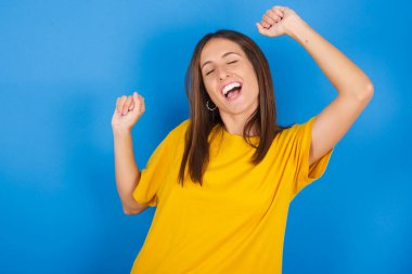 Neşeli genç bir kadının fotoğrafı eğleniyor ve tasasız dans ediyor. Mükemmel bir ruh hali içinde. Hareketler yapıyor. Disko partisinde boş zaman geçirir