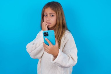 Akıllı telefonundan korkunç haberler okuduktan sonra tırnak yiyen korkmuş genç bir kızın portresi..