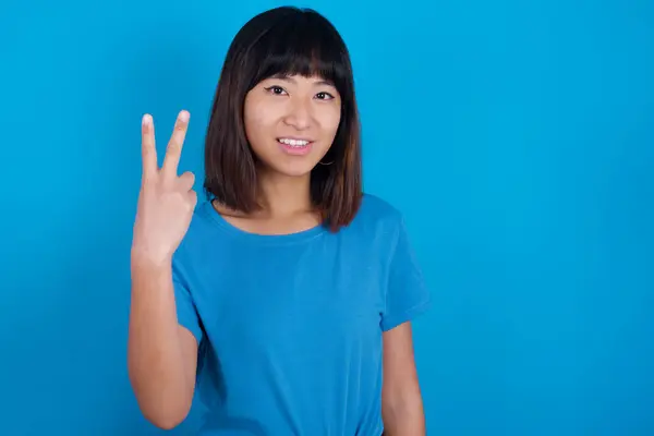 Joven Mujer Asiática Vistiendo Camiseta Sobre Fondo Azul Sonriendo Buscando —  Fotos de Stock