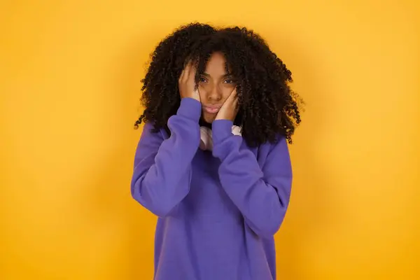 黄色の背景にヘッドフォンを持つ若い表現力のあるアフリカ系アメリカ人女性の肖像画 — ストック写真